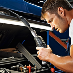 **Automotive repair shop interior, focus on a mechanic using a cordless drill/driver to fix a car part. Good lighting, organized tools visible.**